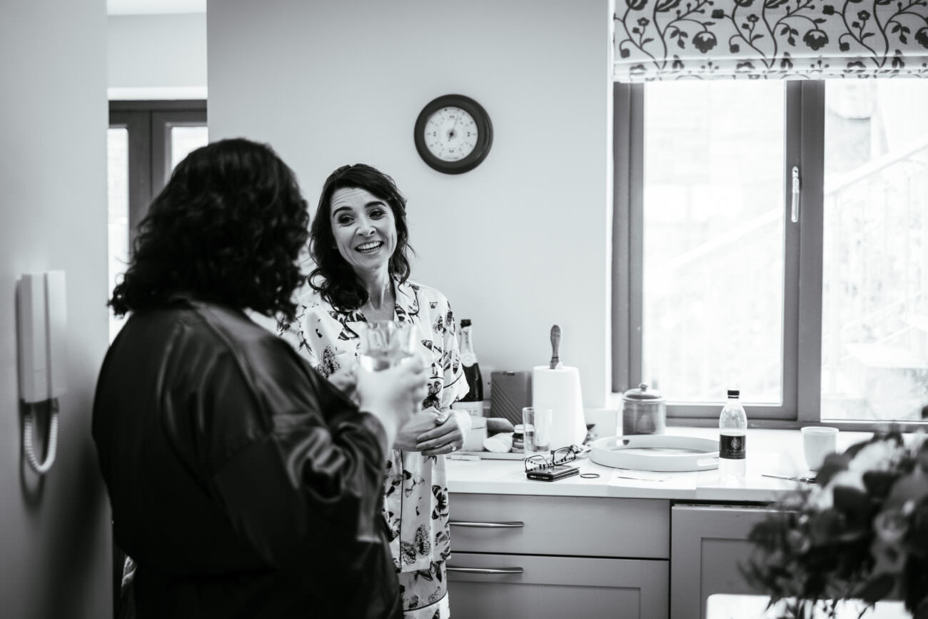 Bride laughing with bridesmaid before leaving for the church in Quilty
