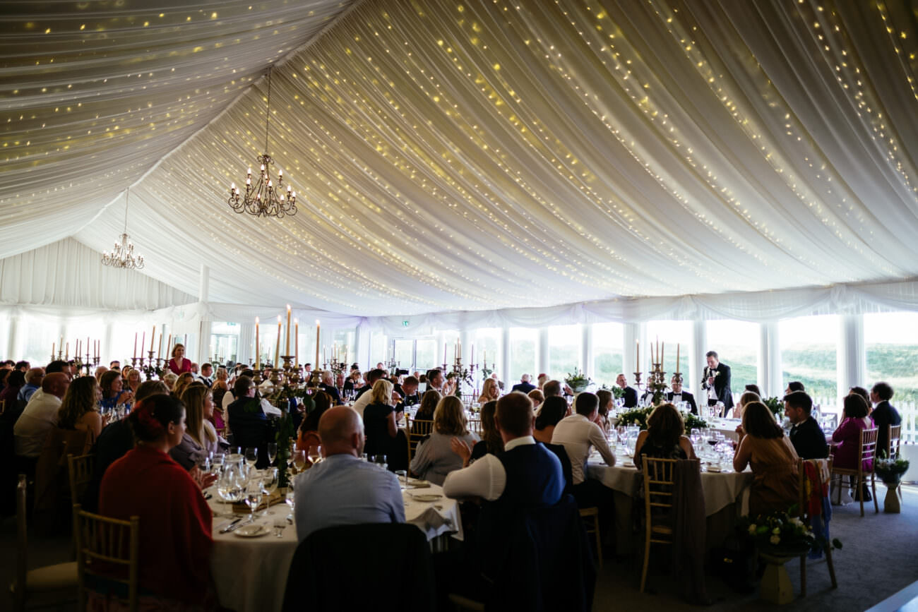 A Trump International wedding reception in a tent with people sitting at tables.