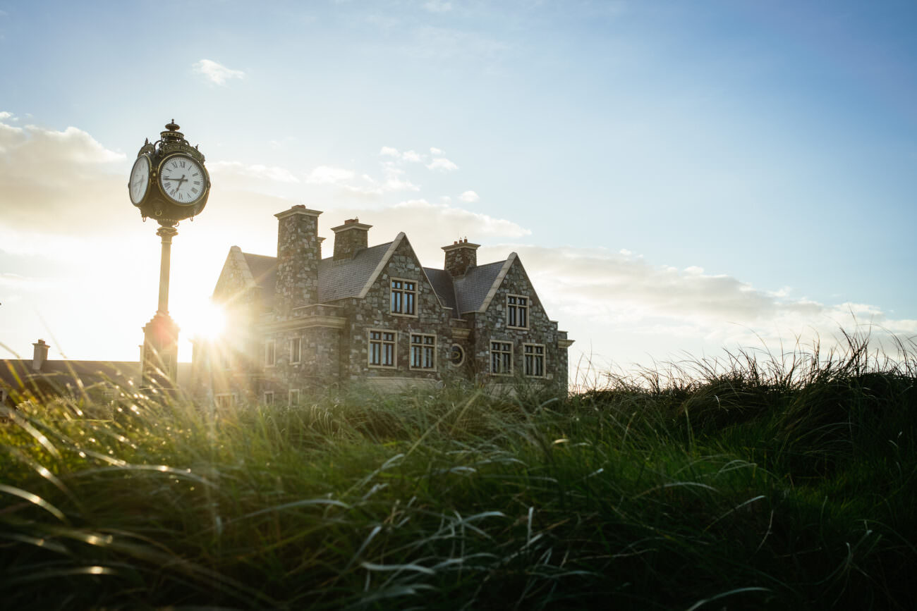 A clock on a pole in front of a house.