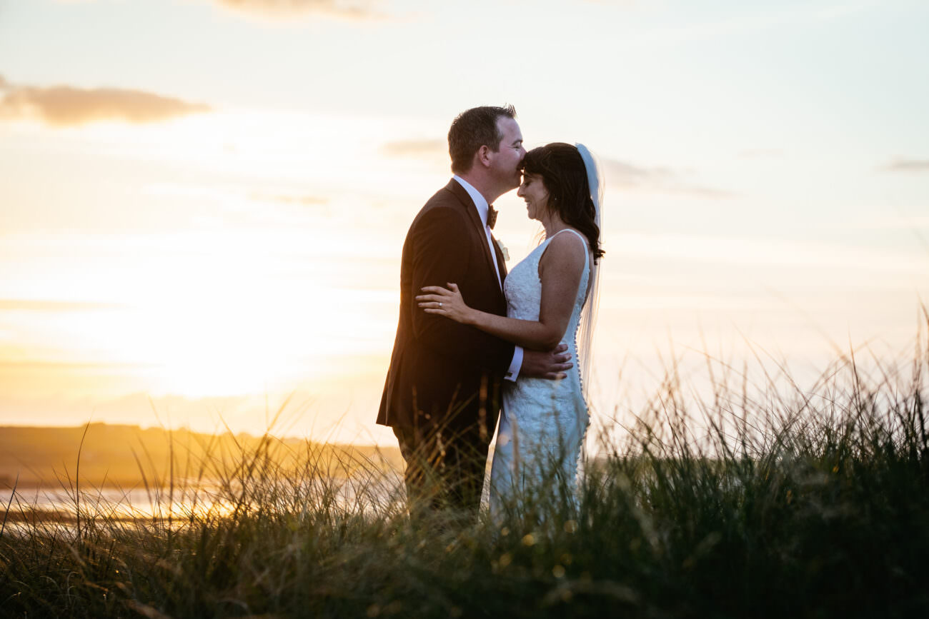 A bride and groom kissing at sunset during their wedding at Trump International Hotel Doonbeg.