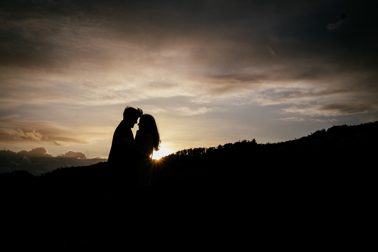 engaged couple embracing at sunset after The Perfect Proposal on Howth Head Dublin
