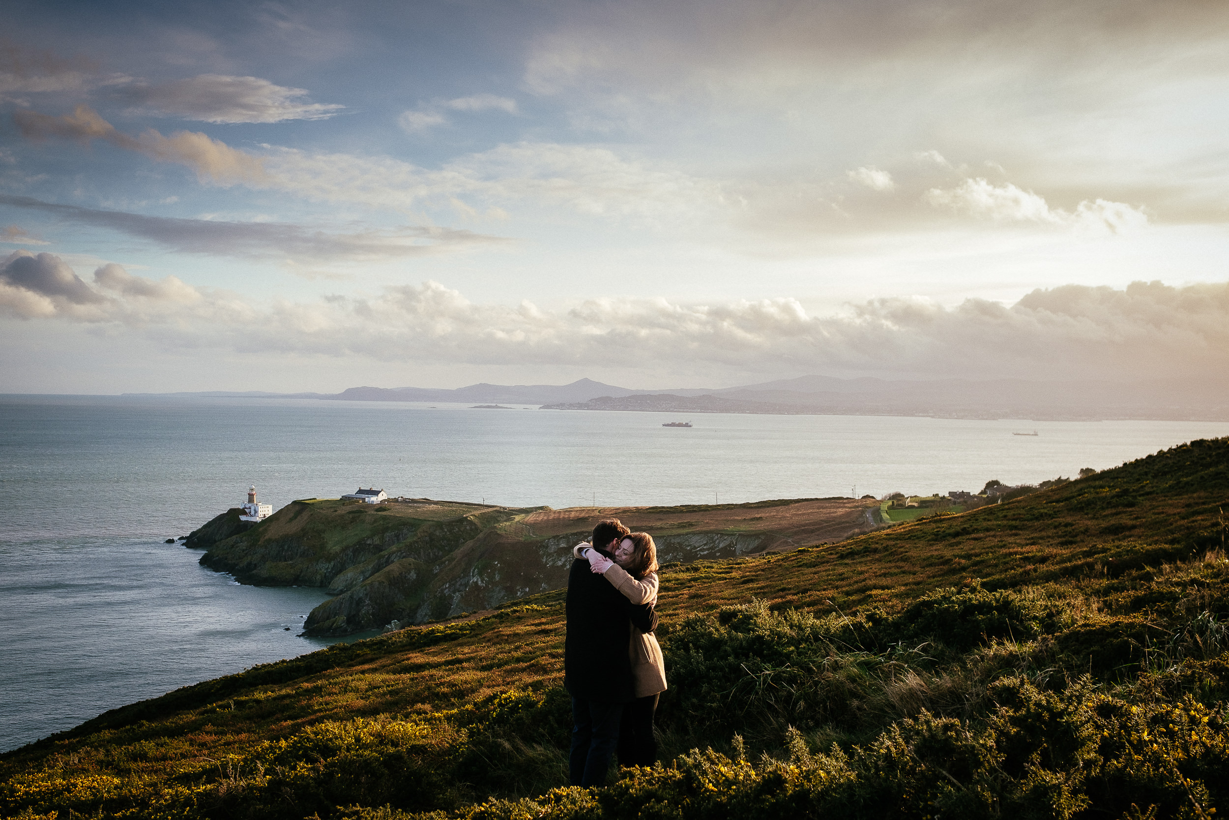 engaged couple hugging on Howth Head after getting engaged