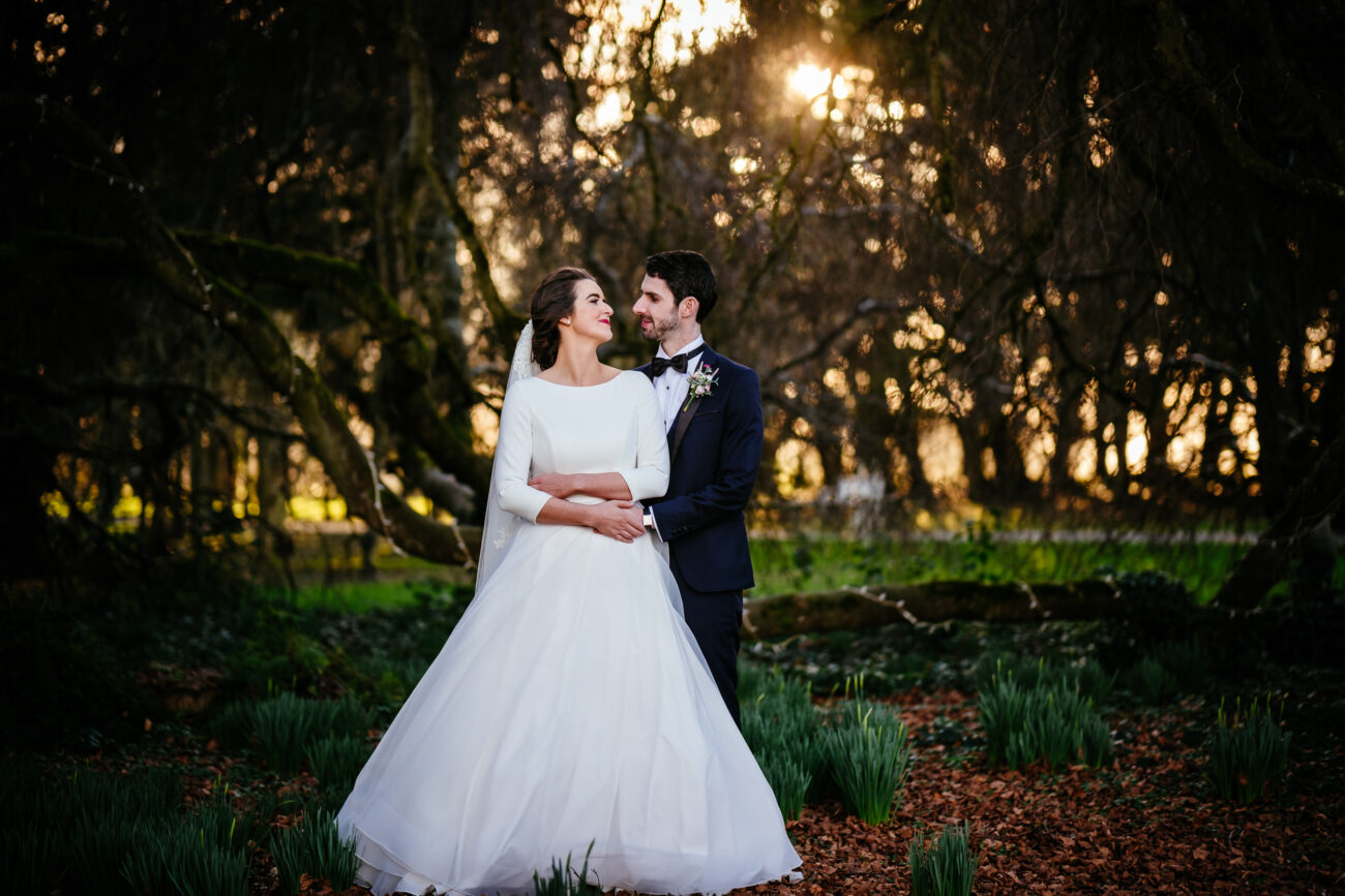 A bride and groom posing for a photo in the woods.