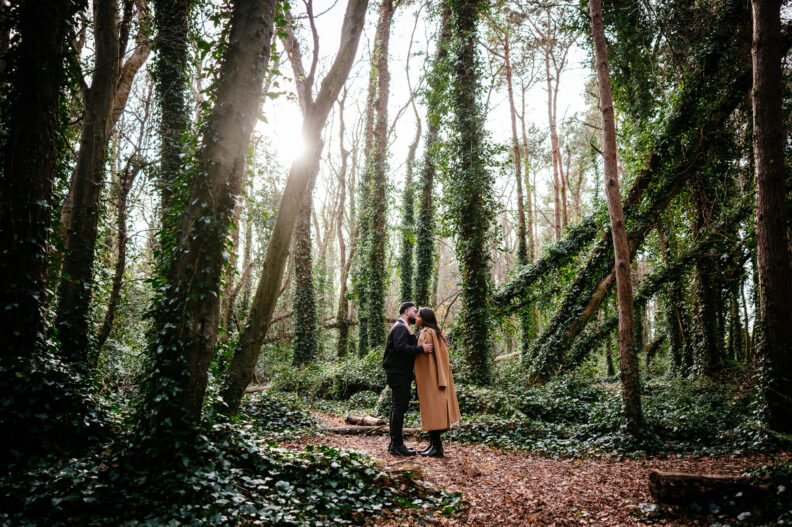 A couple kissing in the woods during their engagement session.