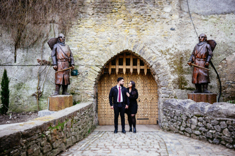 A couple standing in front of a doorway with statues.