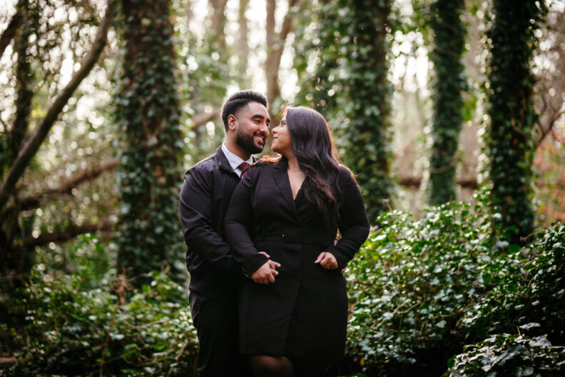 A couple embraces in the woods during their engagement session.