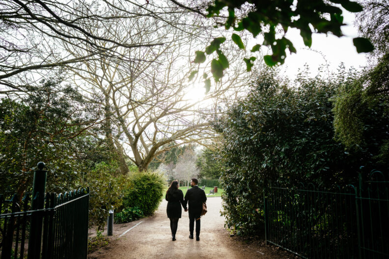 Two people walking down a path in a park.