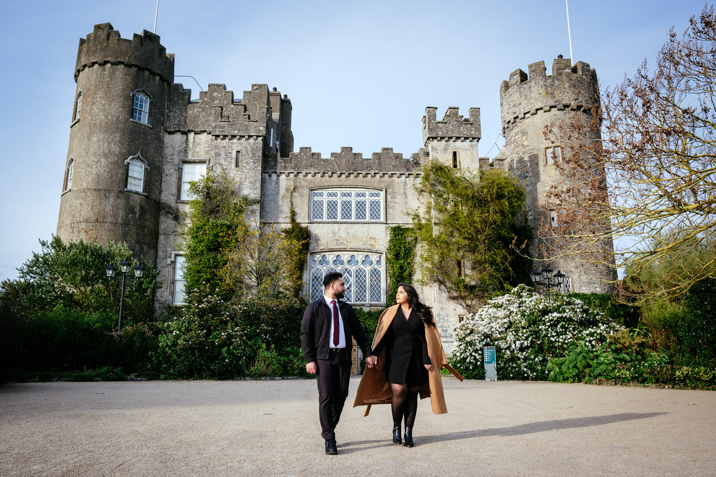 A couple walking in front of Malahide castle during their engagement shoot.