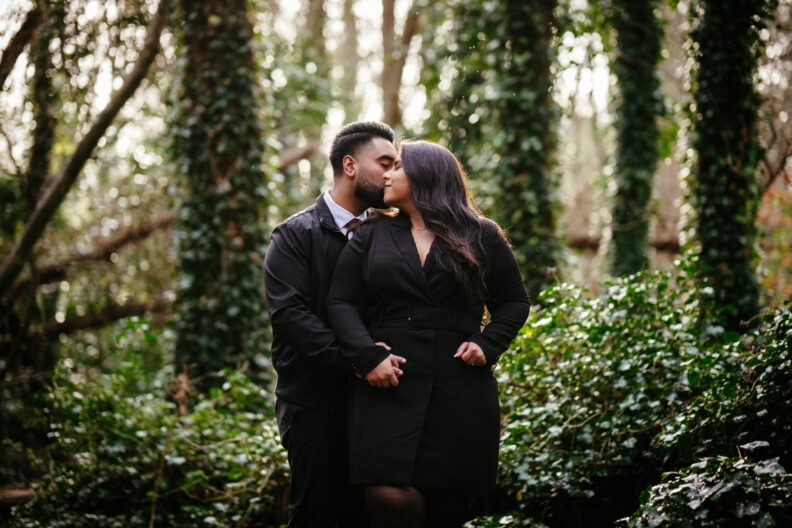 A couple kisses in the woods during their engagement session.
