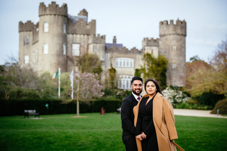 A couple posing in front of a castle.