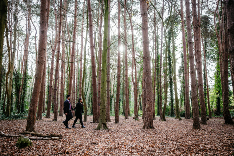 A couple walking through a forest during their engagement session.