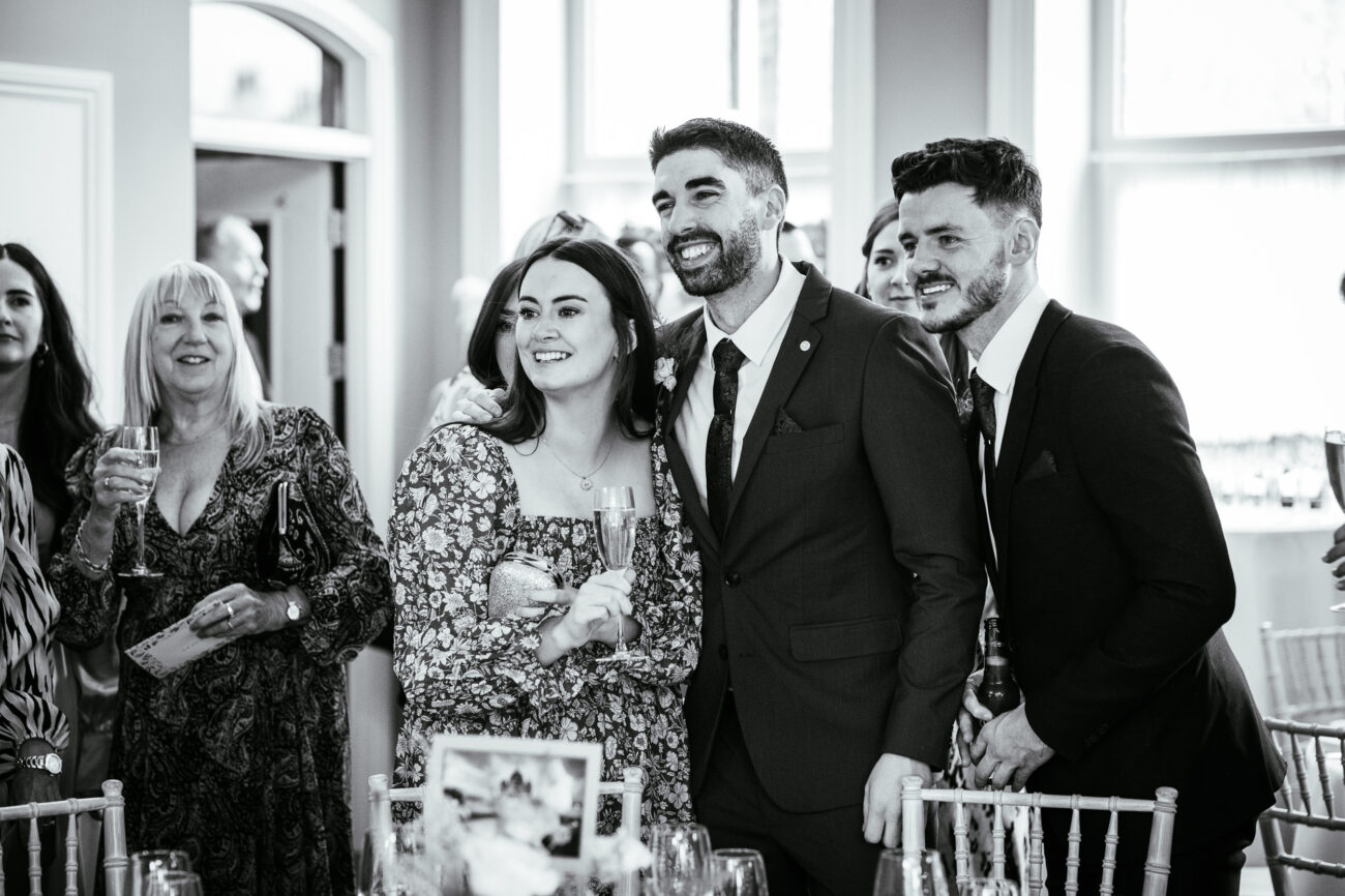A group of people, dressed in formal attire, smile and pose for a photo at an indoor event.