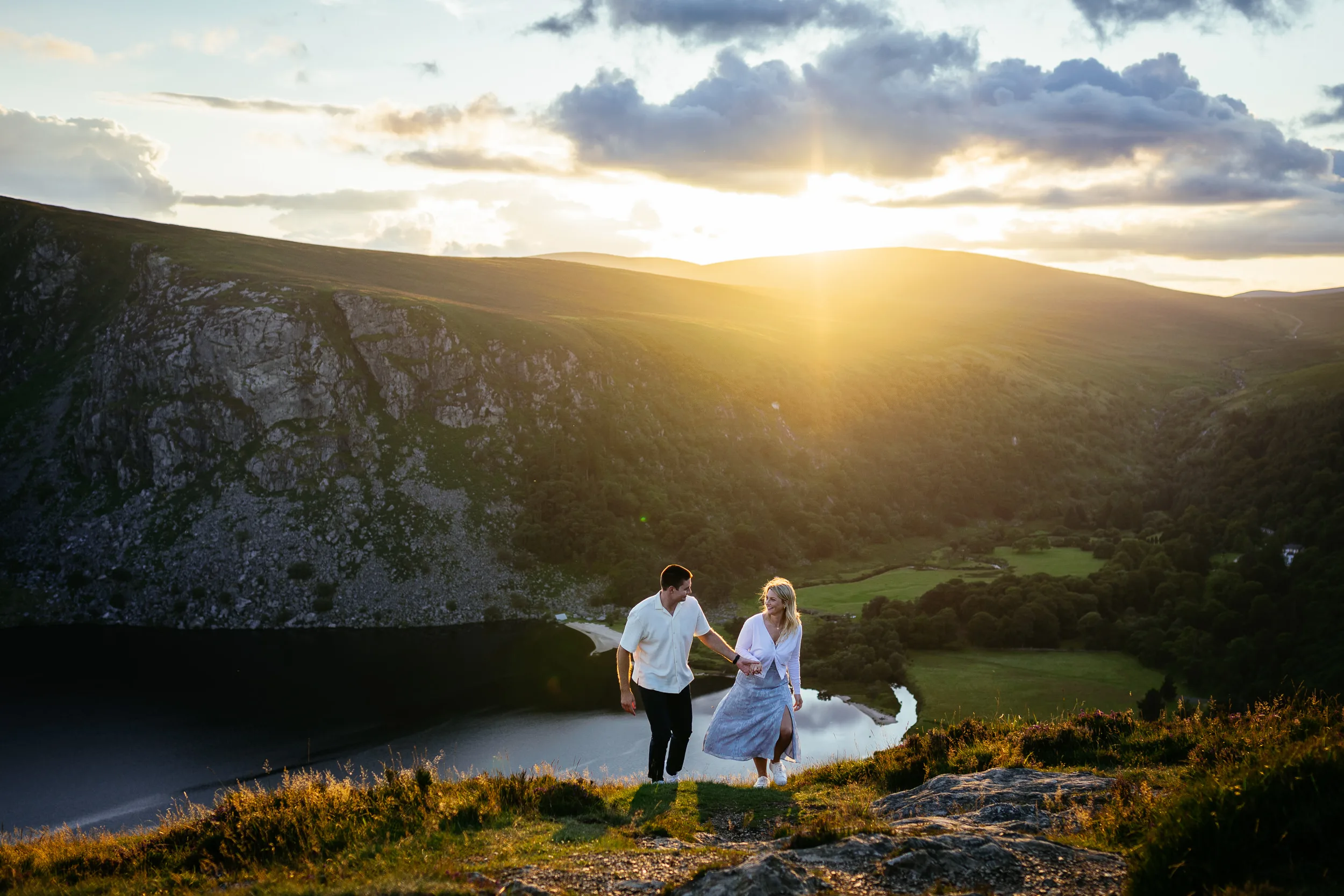 A couple on a hillside overlooking a lake at sunset in the Dublin Mountains