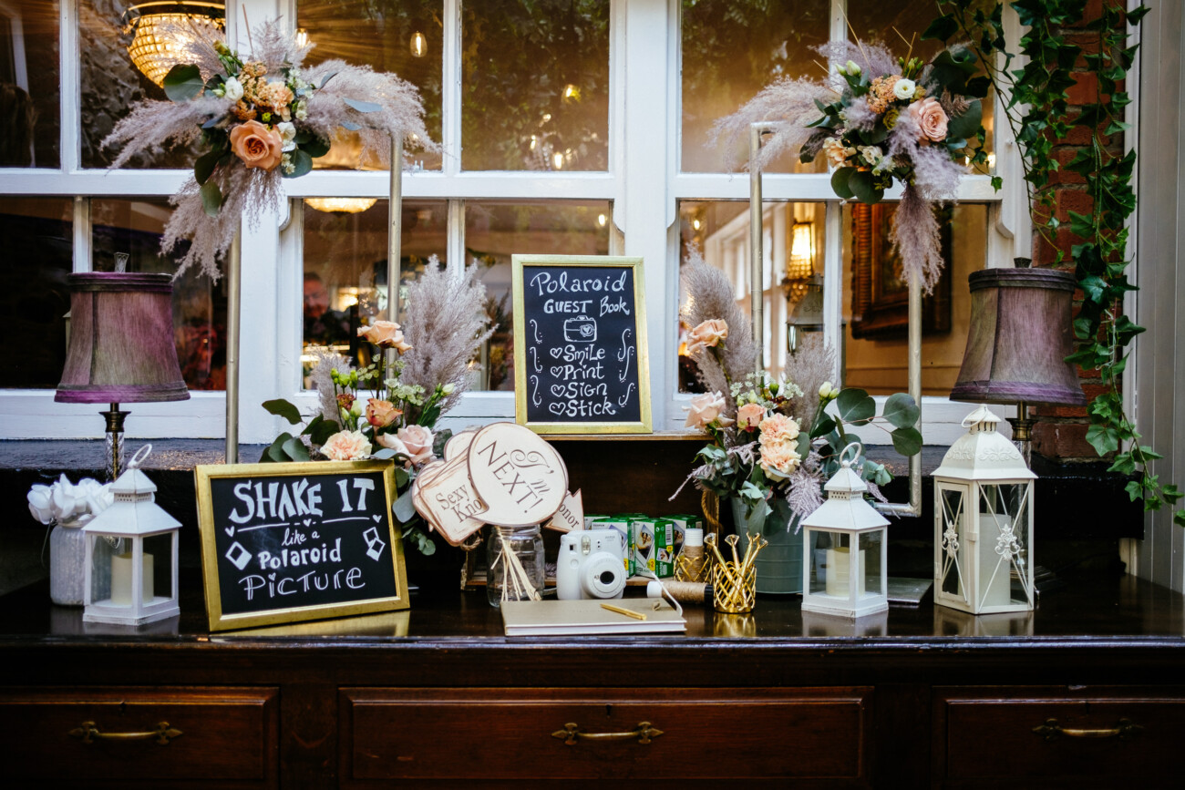 Darver Castle Wedding photo booth setup with floral decorations, lanterns, and signs for a Polaroid guest book.