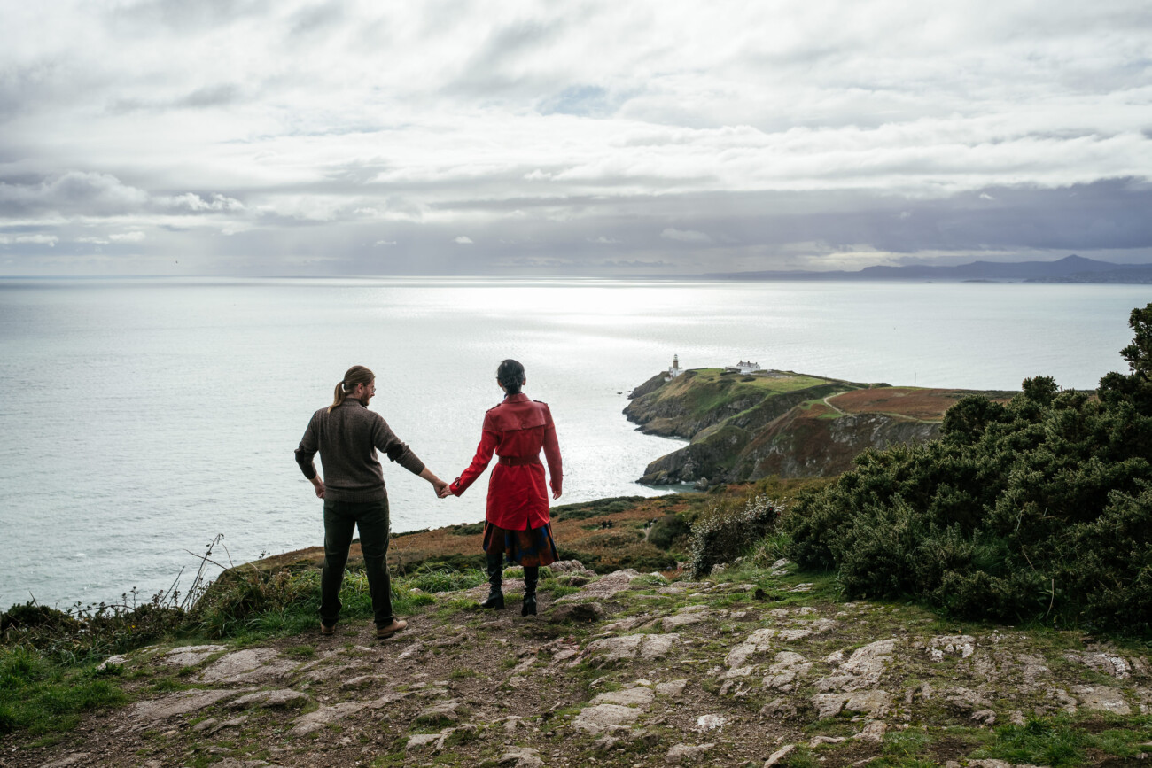 Candid moment of a couple from Canada laughing together on the rugged coastline of North Dublin during a relaxed couple’s shoot.