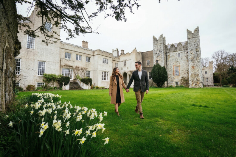 A couple walking across the castle lawn among daffodils