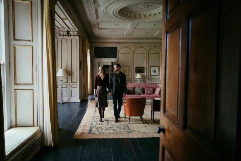 A couple walking through an ornate castle room