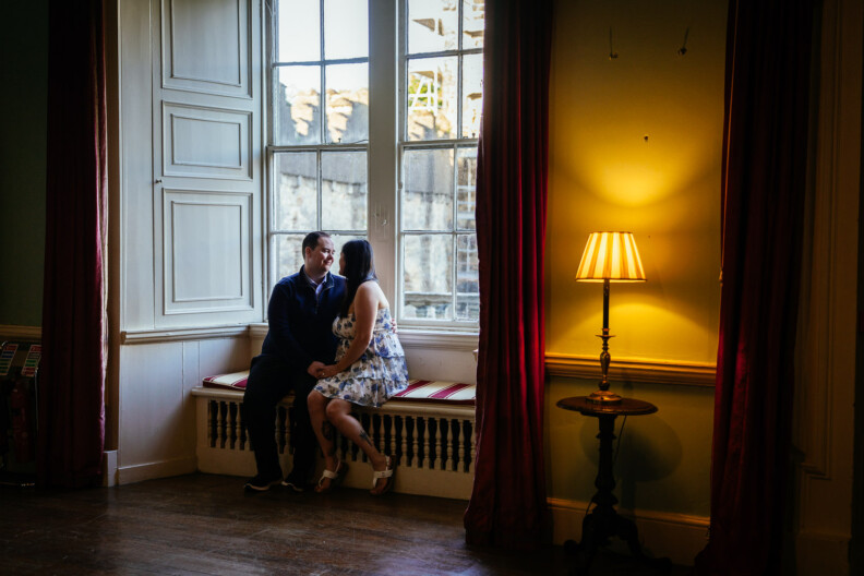 A couple holding hands on a window seat beside a lamp at Howth Castle