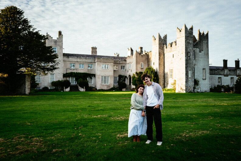 A couple holding hands on the lawn in front of Howth Castle